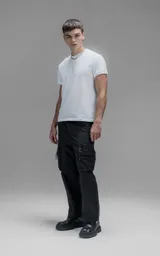 Pantalón cargo oversize de corte relajado, confeccionado en textil técnico resistente de color negro. Presenta bolsillos laterales cargo de gran tamaño con cierres metálicos, bolsillos laterales superiores y bolsillos traseros con broches a presión. Incluye cinturón integrado de cinta de seguridad con hebilla de encastre técnica.