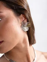 Aros caravanas plateados en forma de flor con diseño calado de filigrana y centro texturizado.