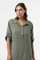 Vestido camisero midi de lino color beige, de calce relajado, con cuello clásico, cierre frontal parcial con botones, mangas 3/4 regulables y bolsillos delanteros.