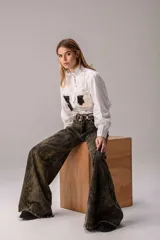 Camisa blanca de manga larga con cuello alto gorguera con volados y detalles de alforzas verticales en el frente. Cuenta con dos bolsillos en el pecho de pelo con estampado de vaca en tonos marrones y blancos.
