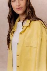 Camisa oversize de denim liviano color amarillo, con cuello camisero, mangas largas con puños, bolsillos delanteros con tapa y ruedo desflecado.
