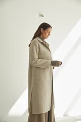 Tapado con cuello solapa y corte recto, color gris. Cierre frontal con botones ocultos, tajos laterales y bolsillos escondidos en corte lateral. Con forro. Tela 100% lana fina sin teñir, diseñada exclusivamente por Don Baez. Hecha 100% en Uruguay.