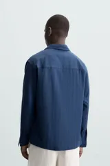 Camisa polo de manga larga con cierre frontal de botones, confeccionada en tejido con textura de rayas verticales sutiles.