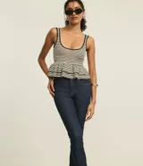 Pantalón skinny jeans azul oscuro con trabillas en la cintura, bolsillos y detalle de pespuntes contrastantes. La pieza también tiene dos botones dorados a cada lado de la barra.