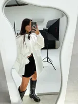 Camisa blanca oversize de manga larga con bolsillos frontales y cuello clásico. Ideal para combinar con shorts y botas altas.