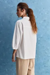 Camisa blanca de algodón, de calce relajado, con cuello camisero, frente abotonado y mangas largas abullonadas.
