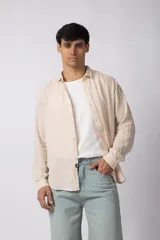 Camisa de lino blanca de manga larga, con cuello clásico y cierre frontal con botones. Corte recto y holgado.