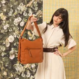 Cartera mochila negra de símil cuero con diseño convertible, bolsillo frontal con cierre y tirador, apertura superior doble y correas ajustables.