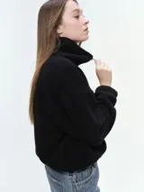 Campera de tela fleece doble, color negro, con cierre frontal completo, cuello alto y bolsillos laterales. Presenta puños y bajo elastizados para un ajuste cómodo.