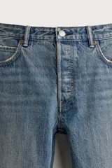 Jeans regular fit de mezclilla negra con efecto lavado, corte recto y tiro medio. Cuenta con diseño de cinco bolsillos y cierre frontal con cremallera y botón.