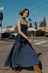 Falda midi azul oscuro, de tiro alto, con corte evasé y textura arrugada o plisada. Presenta un forro interior y cierre lateral oculto.