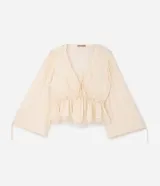 Blusa de viscosa texturada color marfil, con escote en V pronunciado, lazo frontal y corte estilo túnica. Presenta mangas largas abullonadas con puños ajustables mediante tiras y detalles de encaje en el escote, la cintura fruncida y el ruedo.