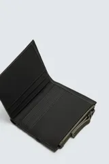 Cartera de acabado engomado en color verde militar y negro. Cuenta con un compartimento principal para billetes, seis ranuras internas para tarjetas y dos externas. Incluye un monedero con cierre de cremallera en uno de los laterales.