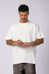 Remera de corte oversized en color marrón, confeccionada en tejido de algodón con textura de micropanal. Presenta cuello redondo con detalle de costura en forma de X y mangas cortas de estilo caído.