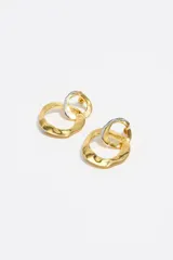 Caravanas de diseño bicolor con textura orgánica, compuestas por dos aros entrelazados de diferentes tamaños. Presentan un acabado metálico en tonos dorado y plateado.