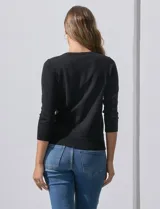 Cardigan blanco de tejido fino con abertura central y botones.