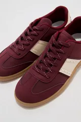 Zapatillas urbanas de color negro con suela de goma marrón, cordones negros con detalles blancos y paneles laterales.