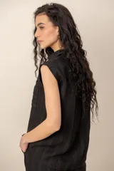 Conjunto compuesto por una blusa sin mangas con cuello camisero, bolsillos frontales y cierre de botones, y un pantalón largo de corte recto y holgado, ambos confeccionados en tejido texturizado de color marrón.