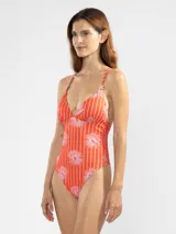 Traje de baño enterizo de lycra color naranja con rayas verticales blancas y estampado de flores rosas. Tiene escote en V, breteles finos y charms florales en los tirantes.