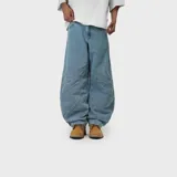 Pantalón jean ultra baggy de diseño amplio y holgado, confeccionado en denim de algodón de calidad premium con textura rústica y costuras decorativas curvadas en las piernas.