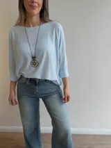 Sweater de punto fino y suave, color gris melange, con diseño amplio y relajado, escote redondo y mangas largas.