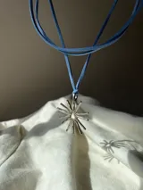 Colgante con dije en forma de sol con rayos, hecho a mano en alpaca, con cordón de gamuza marrón.