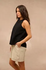 Blusa sin mangas de color negro, corte suelto con costuras verticales decorativas en el frente.