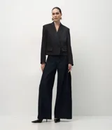 Blazer corto de sastrería marca Cortelle, confeccionado en tejido satinado con acabado brillante. Presenta solapas clásicas, cierre frontal cruzado con botones, bolsillos delanteros con solapa y mangas largas.