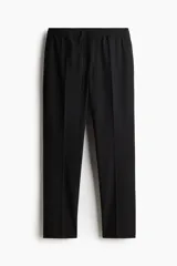 Pantalón tipo jogger de vestir negro, corte slim fit, con pliegues frontales y traseros, cintura elástica con cordón de ajuste y bolsillos laterales y traseros.