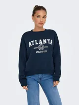 Buzo azul marino de manga larga con cuello redondo y puños acanalados. Presenta un fit holgado y un largo corto. Estampado frontal con la palabra "ATLANTA" en blanco y detalles de texto y escudo.