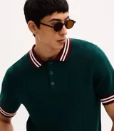 Polo de manga corta confeccionado en tejido de punto texturizado. Presenta cuello, puños y ruedo con diseño a rayas en contraste. Cuenta con una abertura frontal con botones.