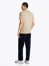 Chomba beige de algodón con cuello clásico, tapeta de dos botones y logo bordado en el pecho.