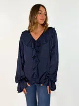Blusa de satén color azul marino con escote en V, detalle de volados frontales y mangas largas con puños acampanados.