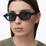 Lentes de sol con armazón de forma ovalada en color negro y cristales polarizados en tono azul claro.