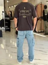 Remera oversize blanca de manga corta, con estampa en la espalda con la inscripción "Concept", un gráfico de pingüino con galera y esferas de líneas.