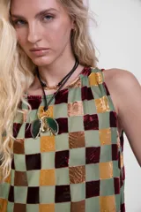 Musculosa de cuello redondo, confeccionada en tejido transparente con diseño de cuadrados de terciopelo a tres colores, con cierre de botones en la espalda.