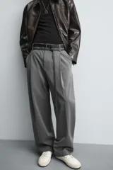 Pantalón de corte balloon fit en color gris, confeccionado en tejido con viscosa. Presenta pliegues frontales, cintura con cinturón integrado a contraste, bolsillos laterales y bolsillos traseros de vivo.