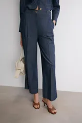 Pantalón de tiro medio confeccionado en denim azul oscuro, con diseño de pierna ancha, pinzas frontales y pespuntes a contraste. Cuenta con cierre frontal de cremallera y botón.