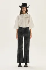 Blusa de algodón color blanco con mangas abullonadas, cuello mao y cierre frontal con botones. Presenta detalles de encaje tipo vainilla en el frente y en la parte superior del pecho.