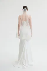 Bustier con escote en V profundo y tirantes finos. Presenta un cuerpo de tul con bordados florales detallados y pedrería, con una base estructurada y una banda lisa en la cintura.