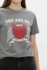 Remera de algodón negra de manga corta y cuello redondo, con estampa frontal que incluye letras rojas y gráficos en tonos dorados.