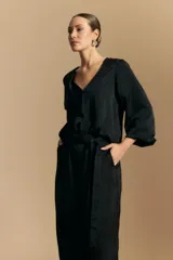 Pantalón ancho de tiro alto color marrón oscuro, con pinzas en la cintura, cinto incorporado y silueta fluida.