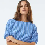 Blusa corta a cuadros azules y blancos, con cuello redondo y mangas cortas abullonadas.