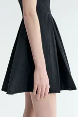 Vestido corto sin mangas en denim negro, con escote redondo, cuerpo entallado y falda acampanada con pliegues.