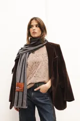 Bufanda tejida en técnica de jacquard con patrón de rayas verticales y parche en paño con bordado.