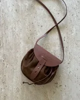 Bandolera negra de cuero gamuzado con solapa de cuero liso y cierre con tira de cuero.