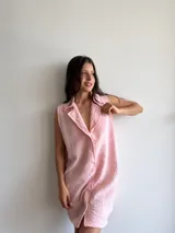 Vestido camisero corto color rosa, sin mangas, con cuello clásico y cierre frontal con botones.