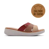 Sandalia casual de cuero con diseño de tiras cruzadas en tonos degradados de rojo, marrón y beige. Presenta una suela de plataforma baja con relieve acanalado y un aplique metálico decorativo en la tira superior.