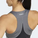 Top deportivo Adidas Techfit, corto, color negro con paneles laterales en gris y blanco. Presenta un corte ajustado, escote alto y espalda deportiva.