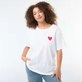 Remera blanca de corte oversize y manga corta, con estampado en la espalda que presenta corazones rojos y la palabra LOVE en letras negras.